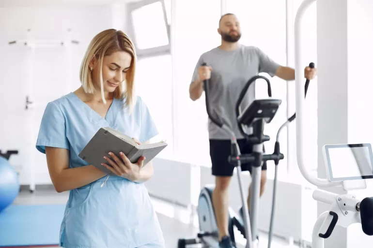 patient doing exercise spin bike gym with therapist