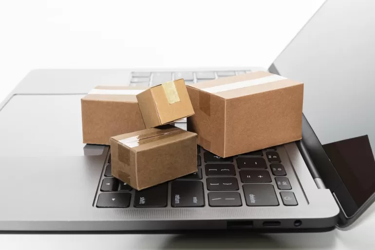 Trzy kartonowe pudełka na laptopie, tworzące stos na laptopie.