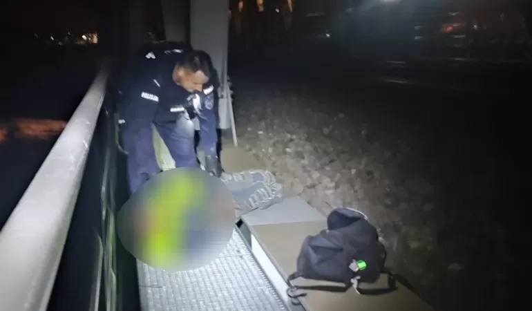 Zdjęcie przedstawia policjanta przy leżącym mężczyźnie, z tyłu widoczny pociąg
